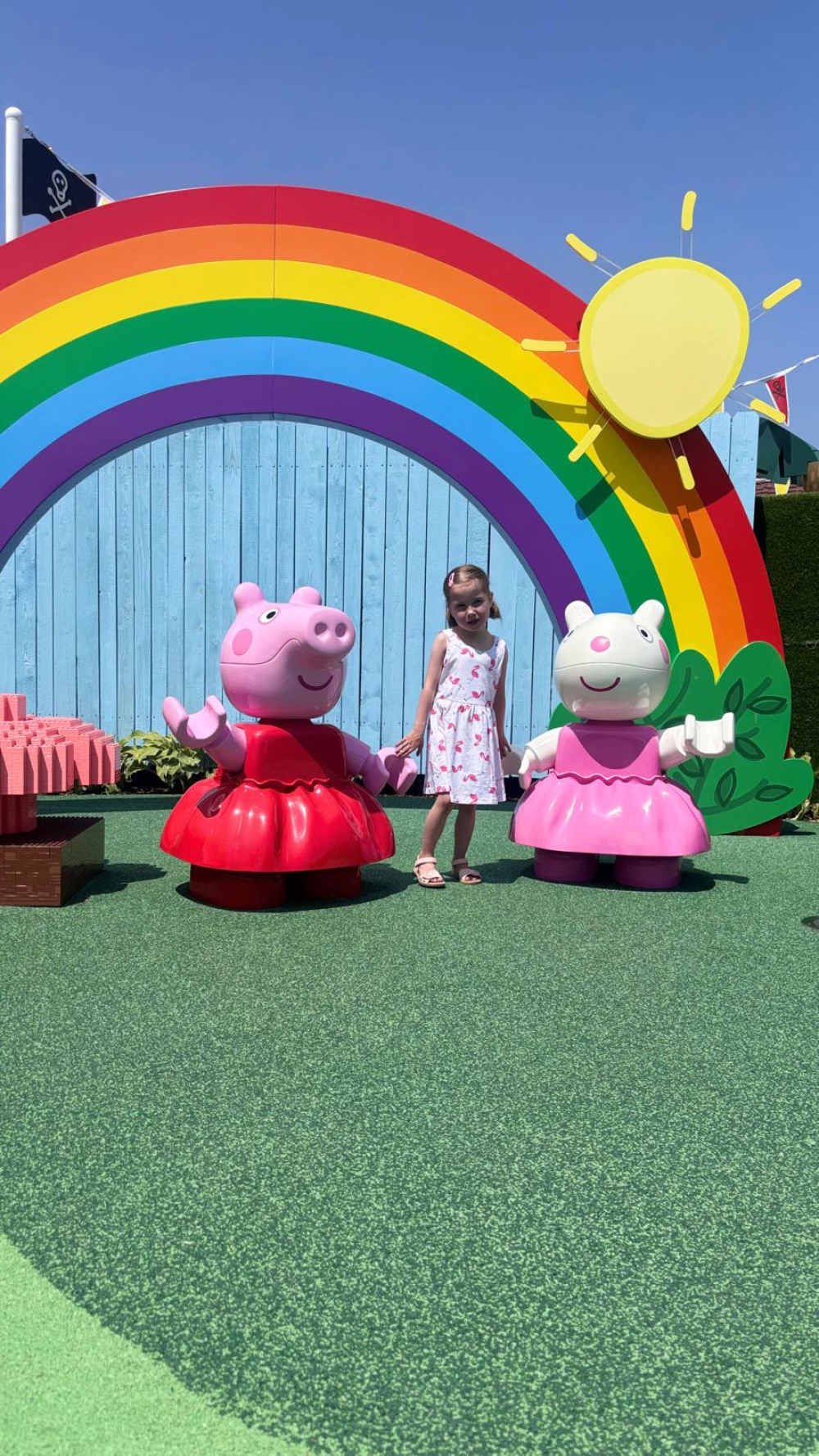 Mila mit zwei Peppa Pig Figuren vor einem Regenbogen